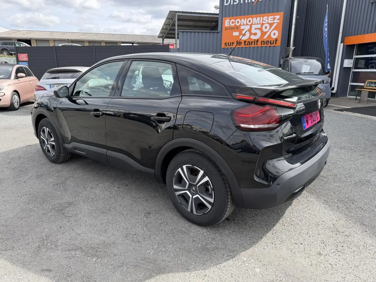 Vue 3/4 arrière droite d'une Citroën C4 électrique noire avec inserts noir brillant et jantes spécifiques.