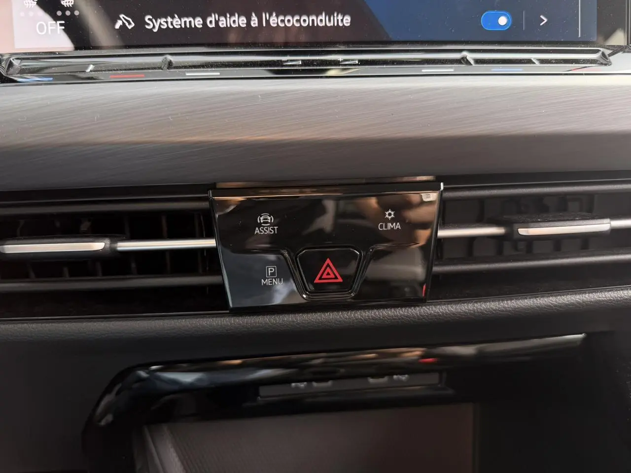 Détail du tableau de bord noir de la Volkswagen Golf VIII 2024 avec commandes d'assistance et climatisation.