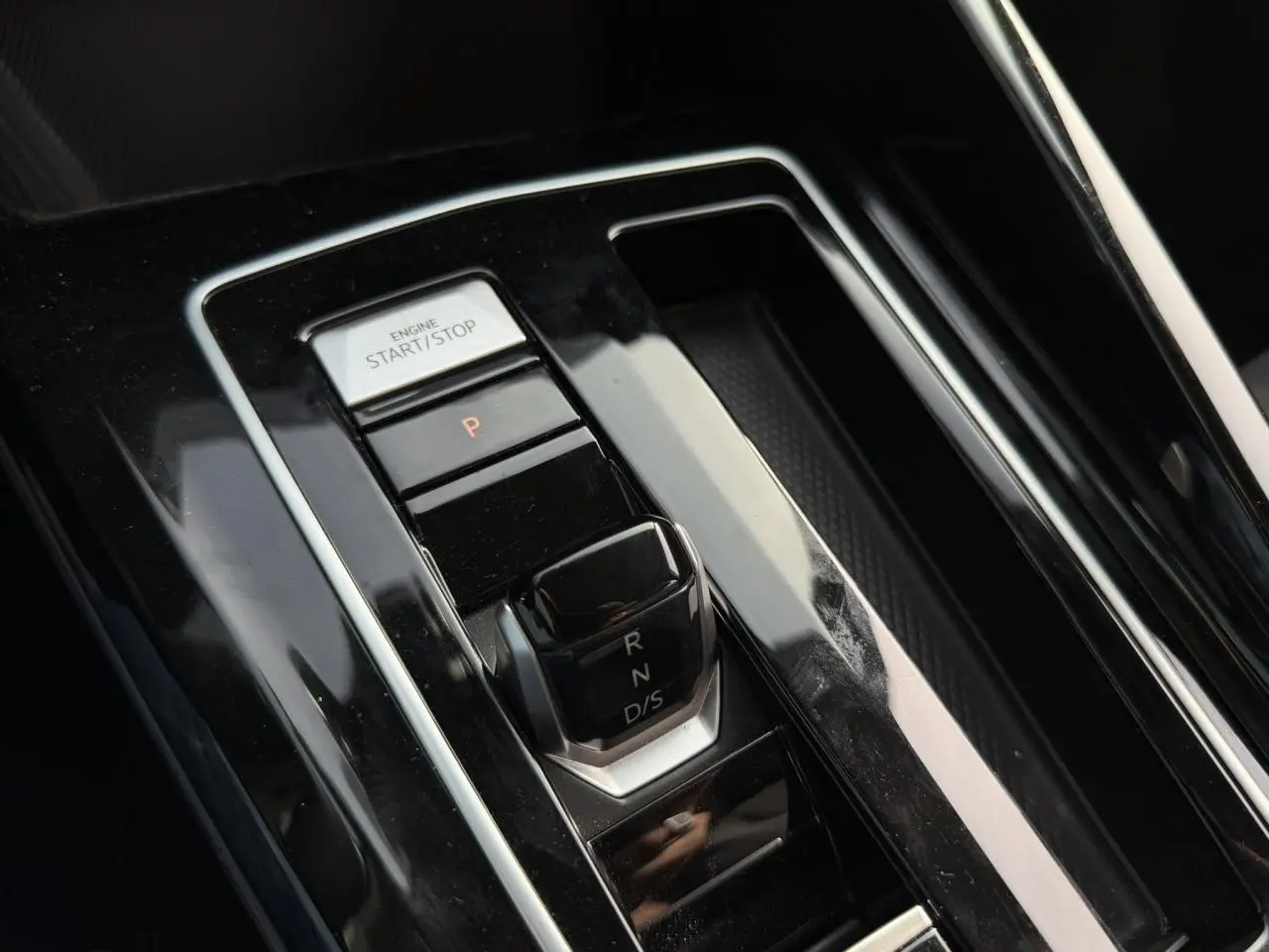Gros plan sur la console centrale de la Volkswagen Golf VIII 2.0 TSI 190 DSG, avec levier de vitesse et bouton start/stop.