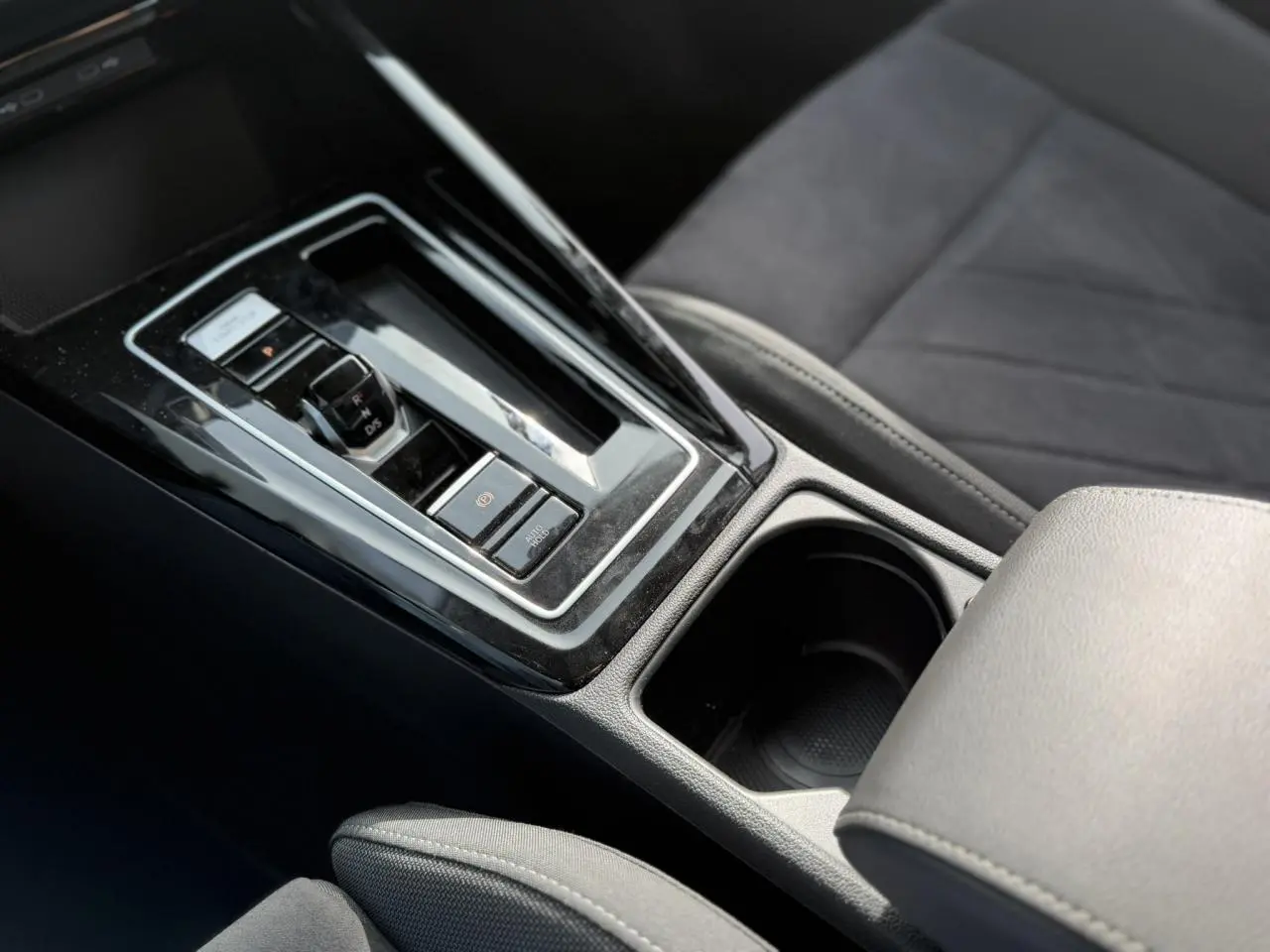 Gros plan sur la console centrale noire brillante et le levier de vitesse automatique de la Volkswagen Golf VIII 2.0 TSI 2024.