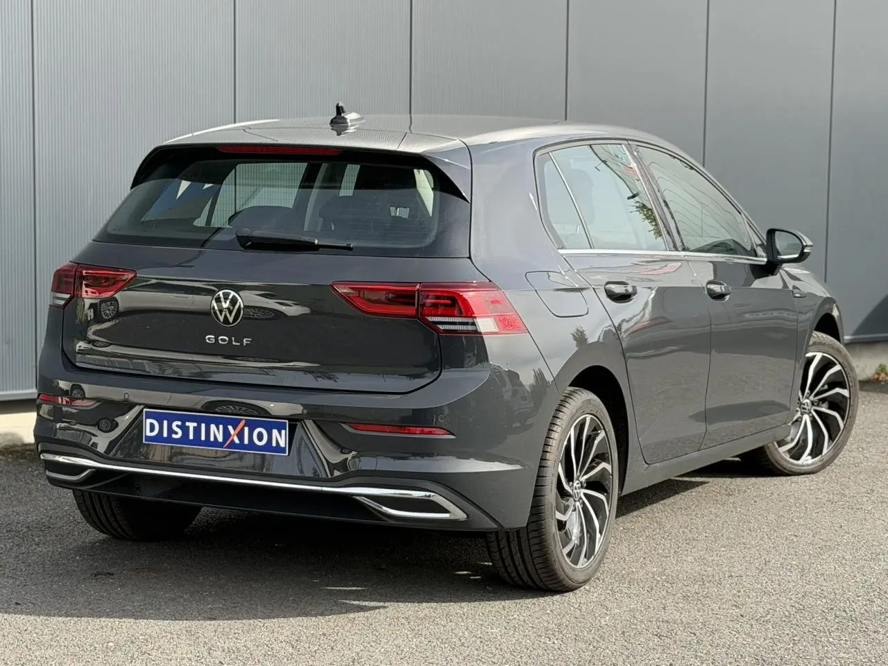 Volkswagen Golf VIII gris Urano vue 3/4 arrière droit, avec jantes alliage et feux arrière LED distinctifs.