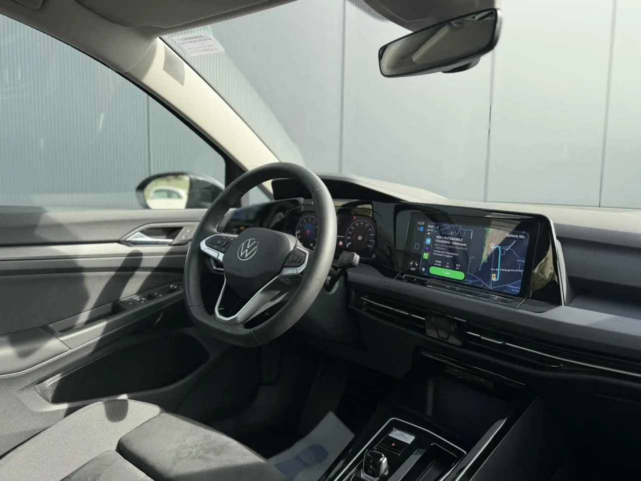 Intérieur de la Volkswagen Golf VIII 2.0 TSI 2024 vu côté conducteur, volant multifonctions cuir et écran tactile.