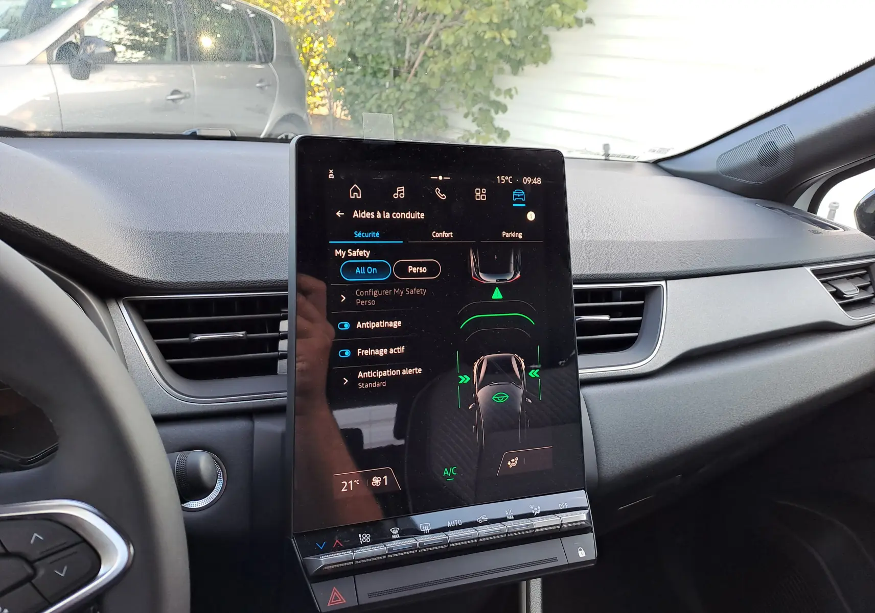 Écran tactile central affichant les aides à la conduite dans l'habitacle gris du Renault Captur blanc nacré toit gris Highland.