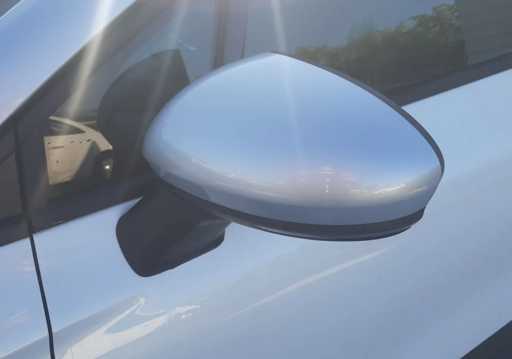 Rétroviseur côté gauche gris Highland sur Renault Captur blanc nacré, vue rapprochée sur la portière avant.