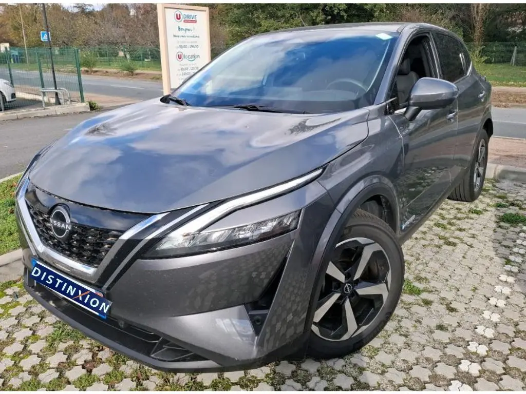 Vue 3/4 avant droit d'un Nissan Qashqai e-POWER gris foncé 2023 avec jantes noires et calandre distinctive.