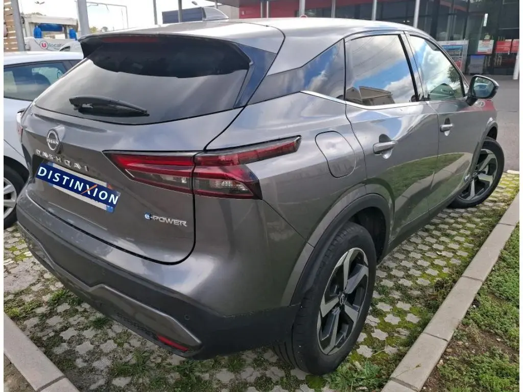 Vue 3/4 arrière droite d’un Nissan Qashqai e-POWER gris foncé 2023 avec feux arrière étirés et jantes noires.
