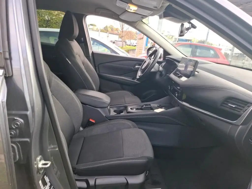 Vue intérieure côté gauche du Nissan Qashqai e-POWER 2023 gris foncé, montrant les sièges avant et le tableau de bord moderne.