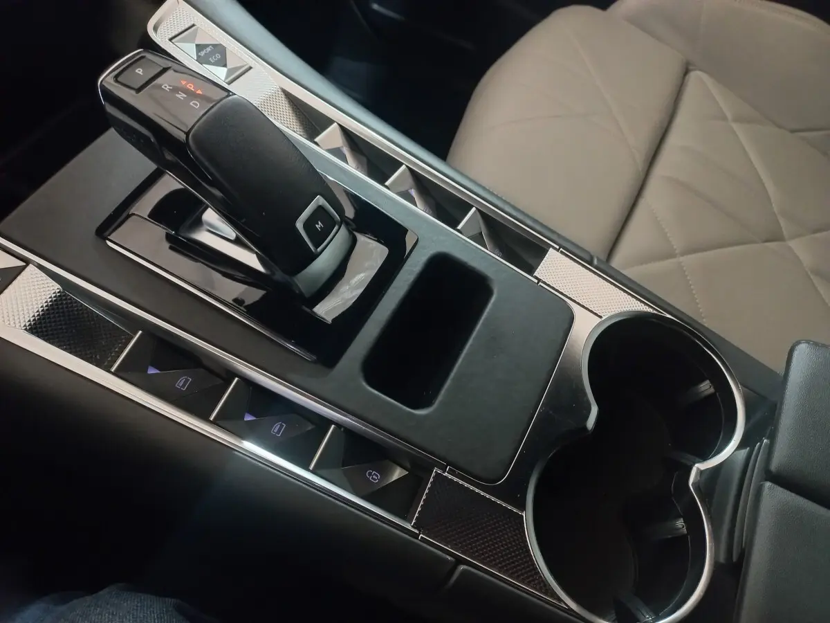 Vue rapprochée de la console centrale intérieure du DS7 Crossback gris foncé, avec levier de vitesse automatique et sièges cuir beige.