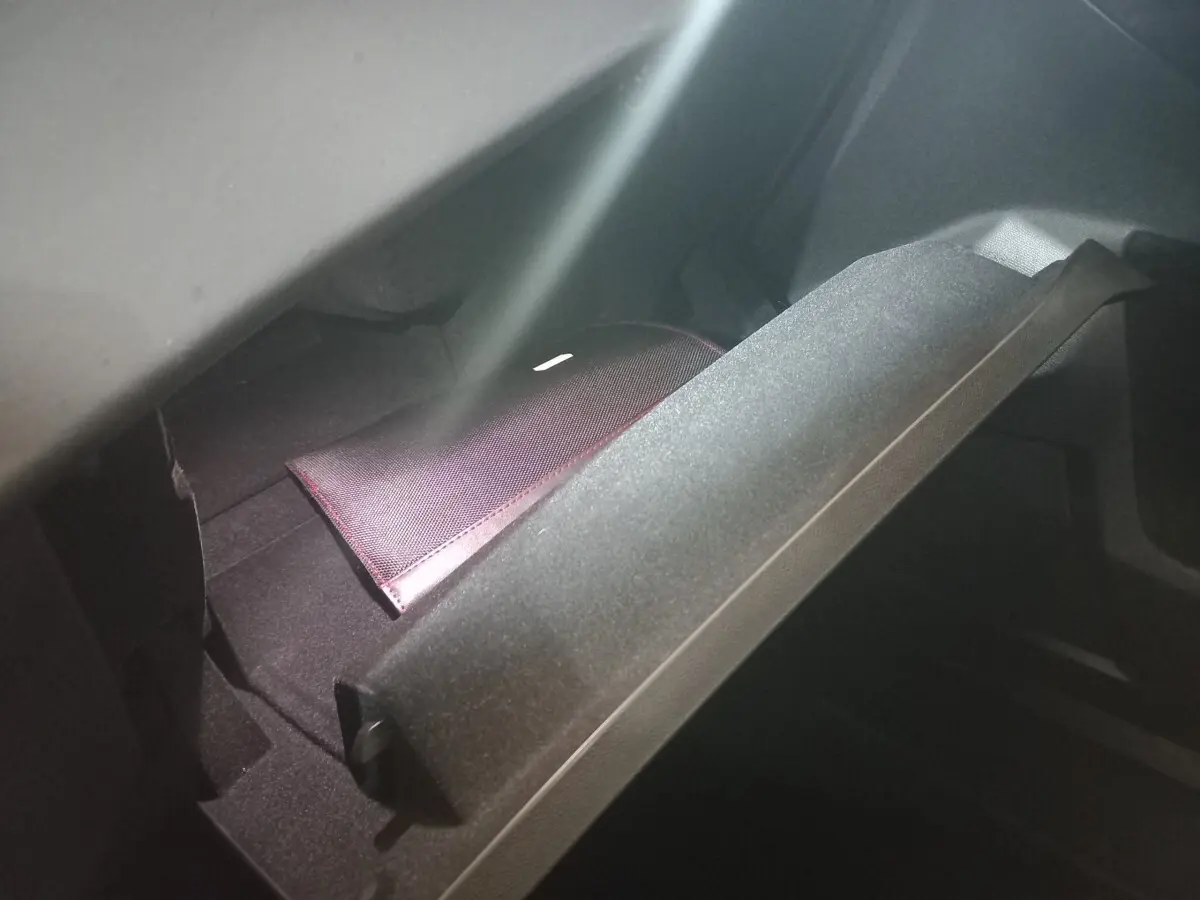 Gant de boîte à gants ouvert montrant un étui noir avec surpiqûres rouges dans un DS7 Crossback gris foncé.