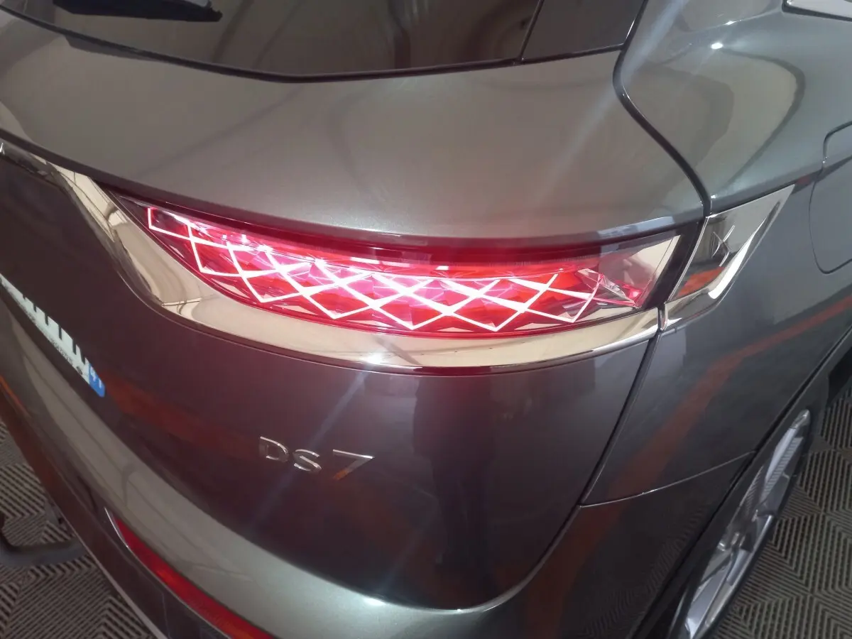 Vue arrière droite du DS7 Crossback gris foncé mettant en valeur son feu arrière à motif lumineux géométrique distinctif.