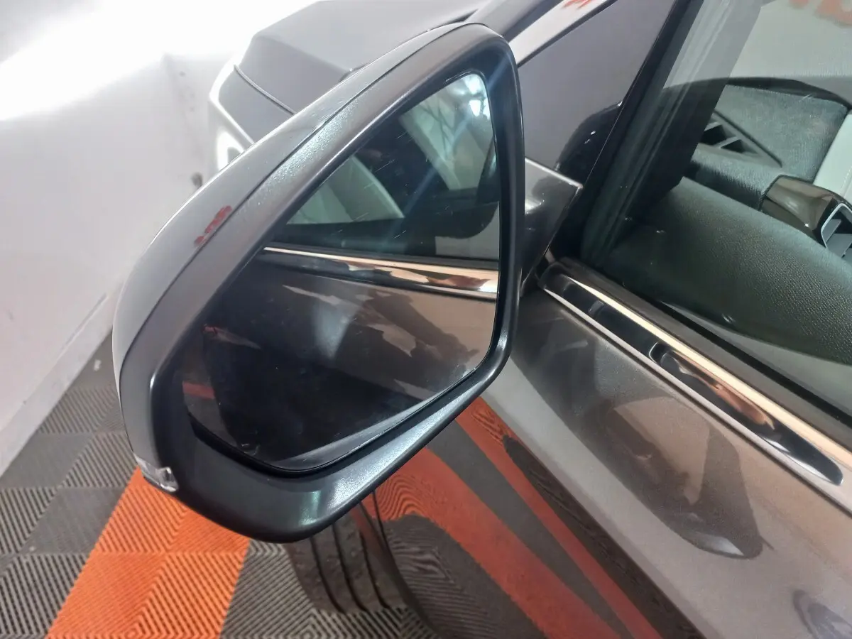 Rétroviseur côté gauche du DS7 Crossback gris foncé, avec reflet de l’habitacle et carrosserie visible en arrière-plan.