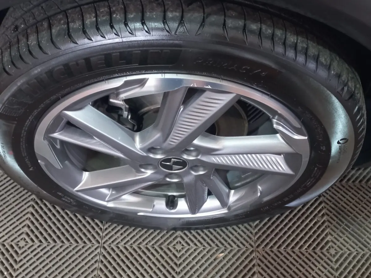 Gros plan sur la jante alliage argentée et le pneu Michelin d’un DS7 Crossback gris foncé, vue latérale.