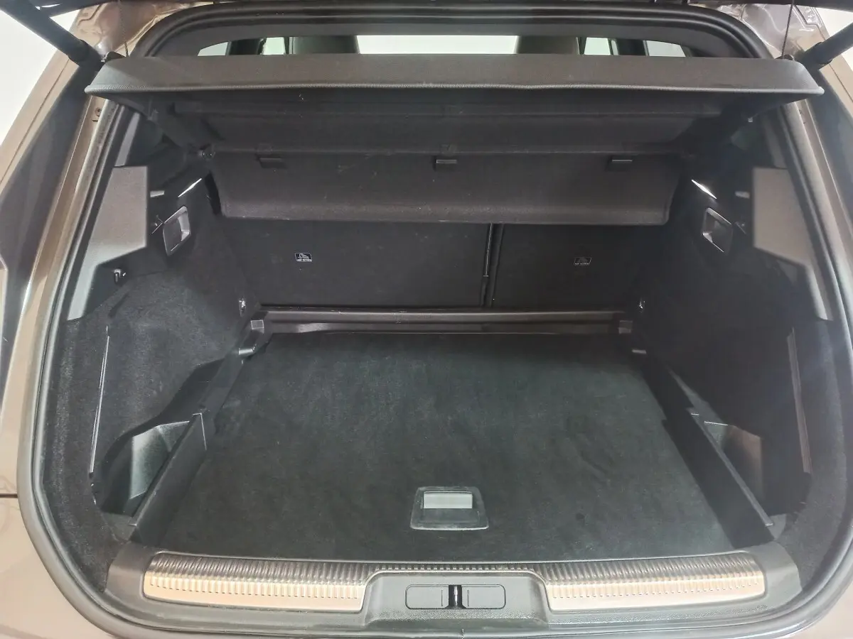 Vue arrière du coffre spacieux et propre du DS7 Crossback gris foncé, avec cache-bagages et seuil de chargement inox.