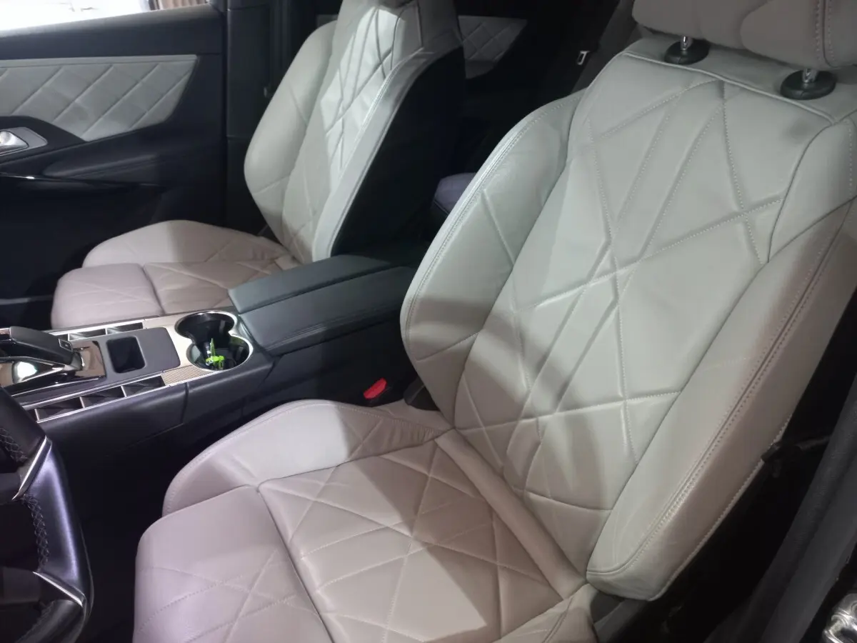 Vue rapprochée des sièges avant en cuir beige matelassé du DS7 Crossback 2021, avec console centrale et accoudoir noir.