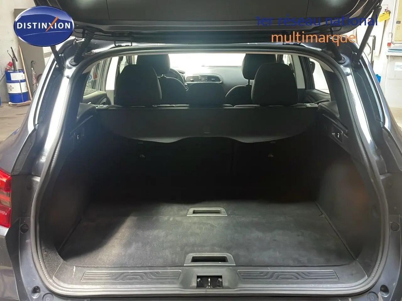 Coffre ouvert vu de l'arrière d'un Renault Kadjar gris titanium métal, montrant l'espace de chargement et les sièges arrière.