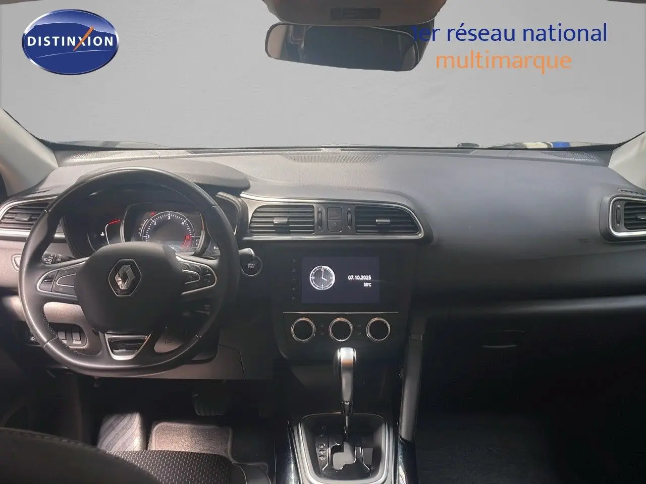 Vue intérieure frontale du tableau de bord du Renault Kadjar gris titanium, avec volant multifonction et écran central allumé.
