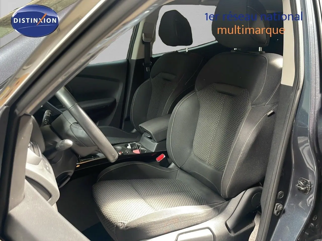 Vue intérieure côté conducteur du Renault Kadjar gris titanium, mettant en valeur les sièges en tissu noir et la console centrale.