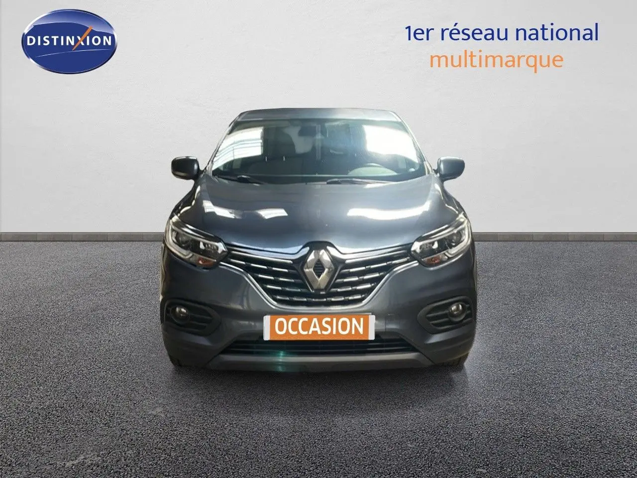Vue avant d’un Renault Kadjar gris titanium metal avec calandre chromée et phares LED allumés sur fond neutre.