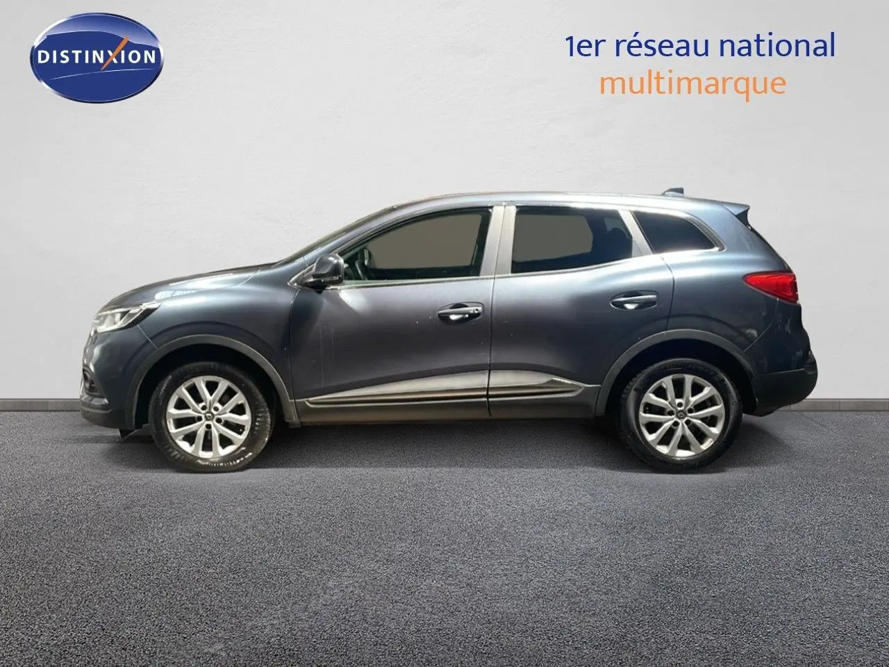 Profil droit d’un Renault Kadjar gris titanium métal 2021, SUV compact avec jantes alliage et vitres teintées.