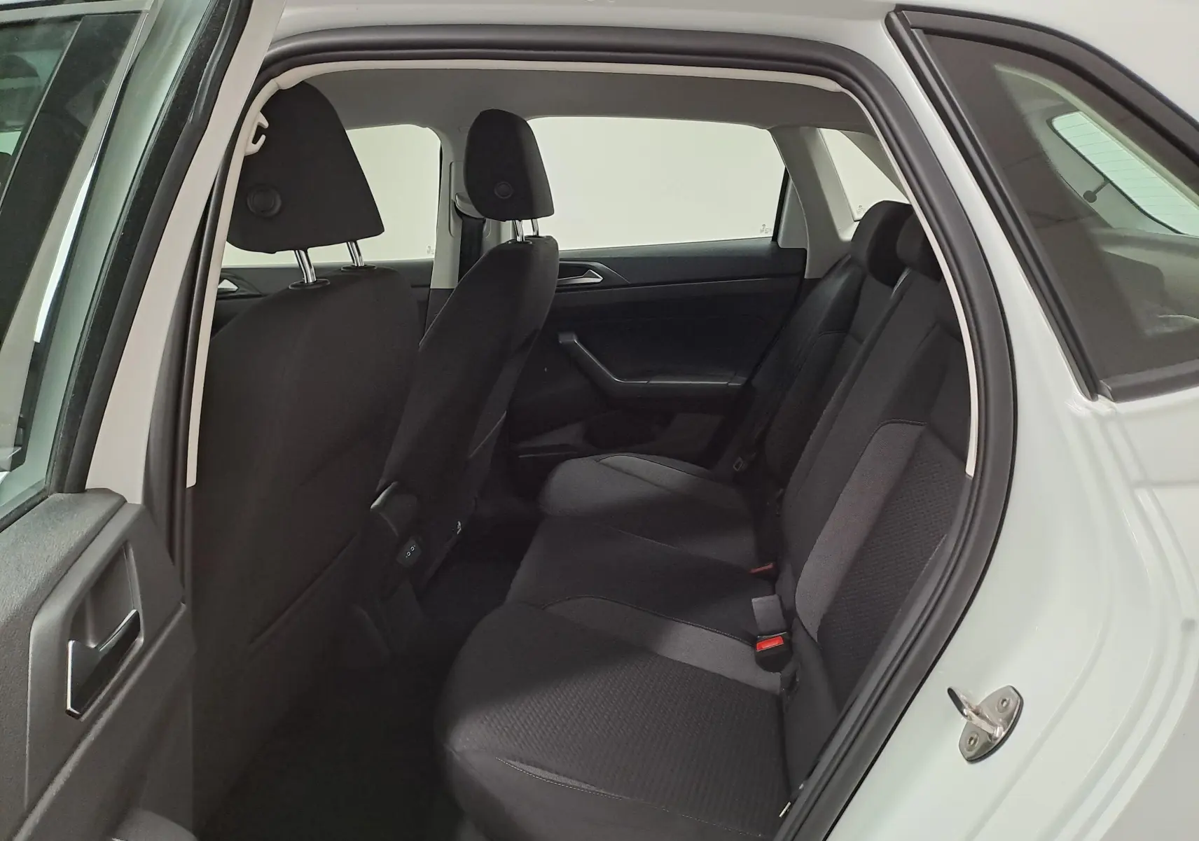 Vue intérieure côté arrière droit de la Volkswagen Polo 2024 blanche, montrant les sièges arrière en tissu noir.