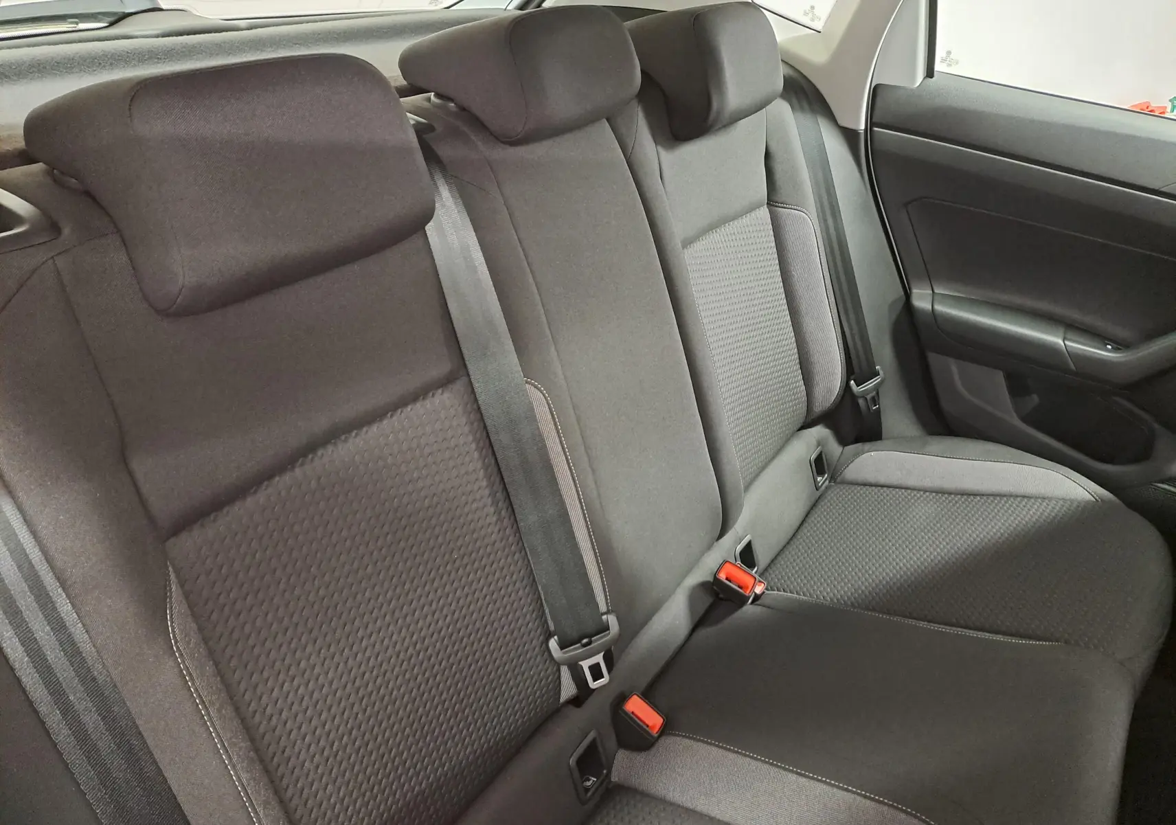 Vue intérieure du siège arrière droit de la Volkswagen Polo 2024 blanc pur, avec ceintures de sécurité et appuie-têtes noirs.