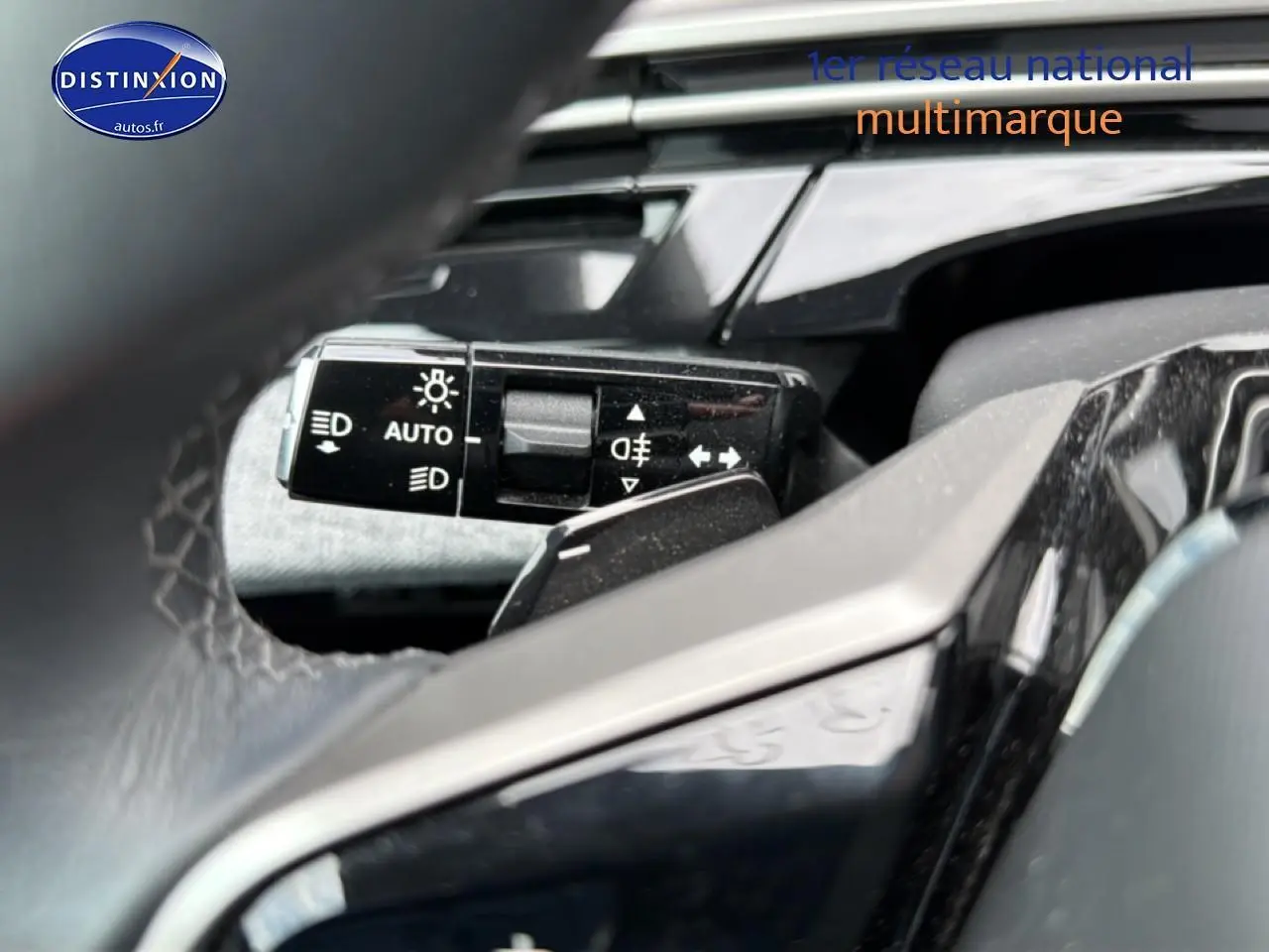 Gros plan sur la commande des phares et clignotants du Peugeot 3008 gris titane, vue depuis le volant cuir.