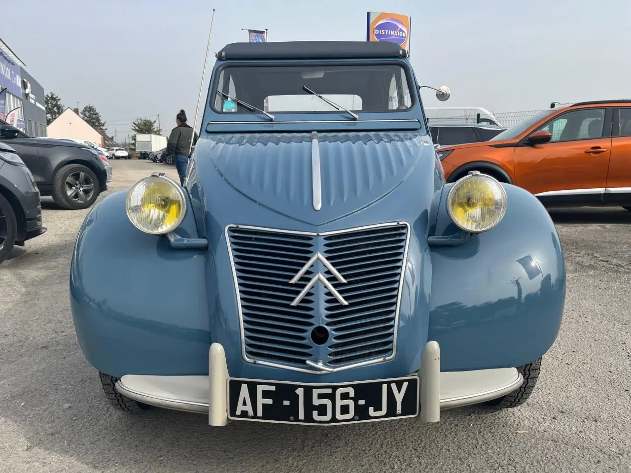 Vue de face d'une Citroën 2 CV bleu clair de 1960 avec phares jaunes caractéristiques et calandre en métal chromé.