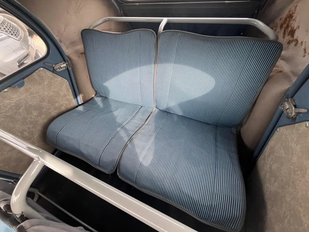 Vue intérieure arrière du Citroën 2CV 1960 montrant la banquette à rayures bleues et blanches dans un habitacle bleu clair.