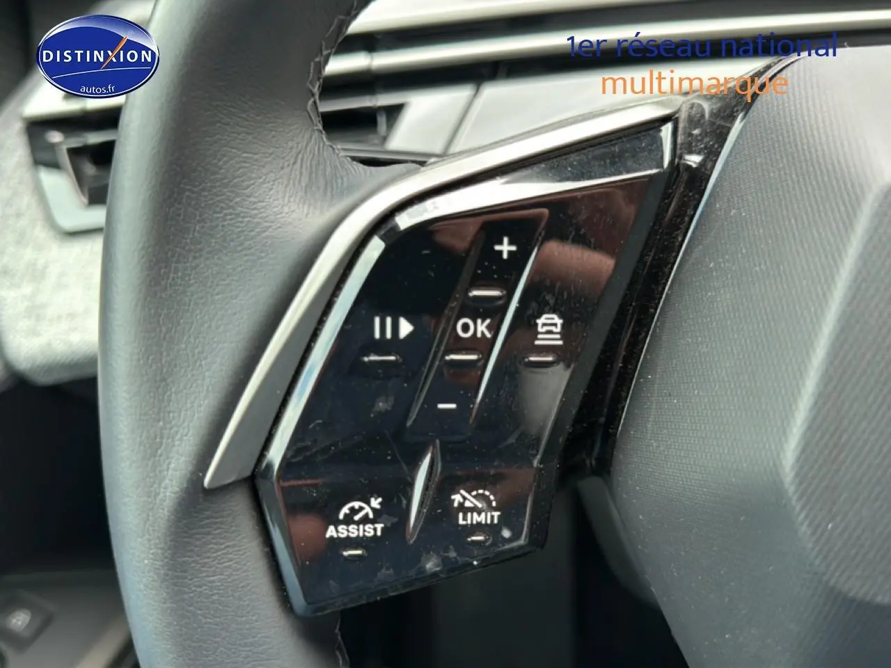 Gros plan sur les commandes multifonctions noires du volant cuir du Peugeot 3008 gris titane, version 2025 hybride.
