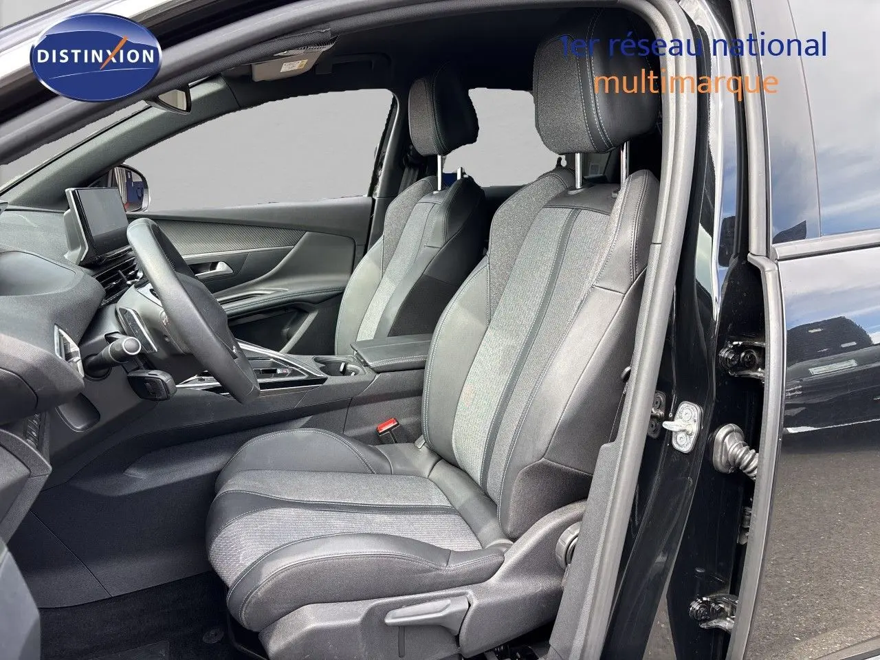 Vue intérieure côté conducteur du Peugeot 3008 Hybrid 180ch Allure 2024 noir métal, sièges tissu et cuir bicolore.