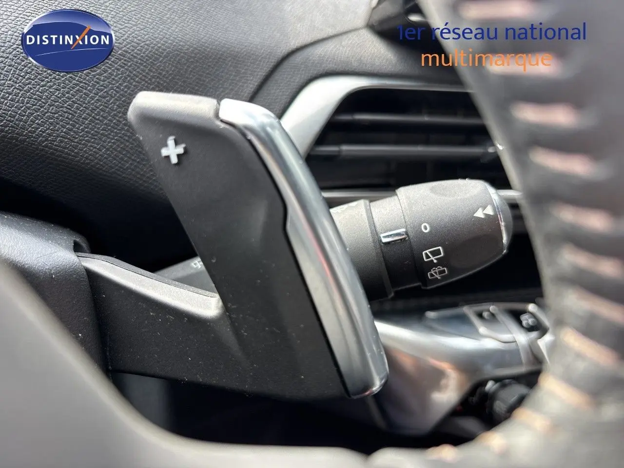 Gros plan sur la palette de changement de vitesse + du côté gauche du volant d’un Peugeot 3008 noir métal 2024 hybride.