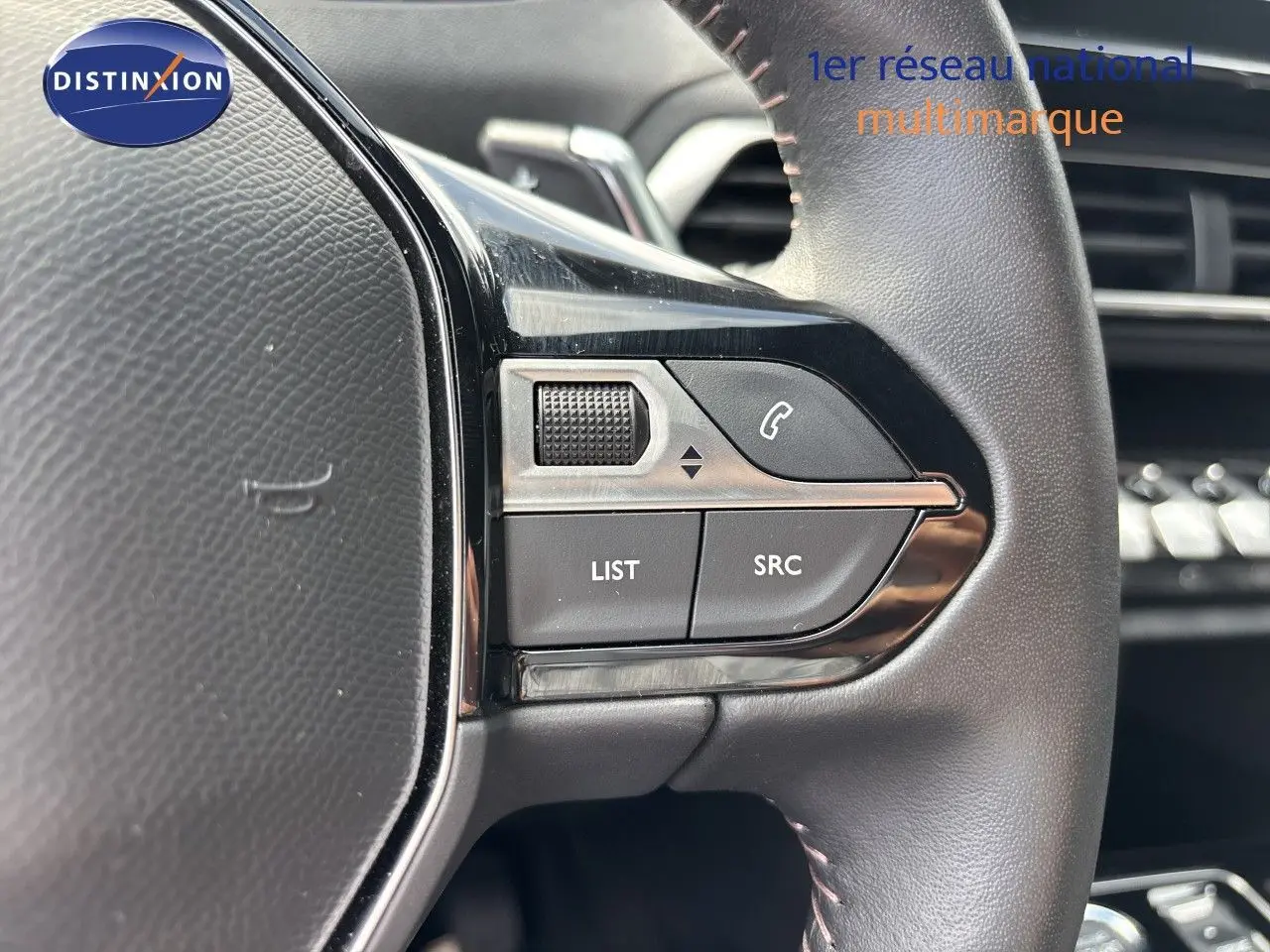 Gros plan sur les commandes gauche du volant cuir noir du Peugeot 3008 Hybrid 2024, avec boutons LIST et SRC visibles.