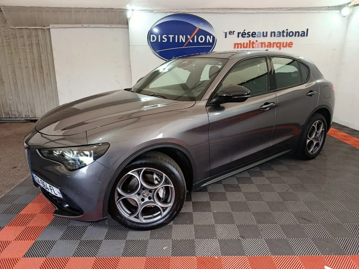 Vue 3/4 avant droite de l'Alfa Romeo Stelvio gris foncé 2024 avec jantes spécifiques et phares LED ellipsoïdaux.