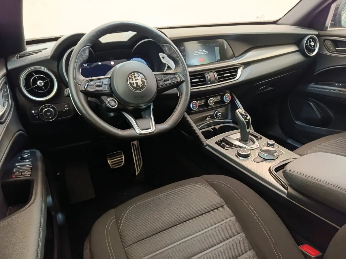Intérieur noir de l'Alfa Romeo Stelvio 2024 vu côté conducteur, avec volant cuir et écran tactile central.