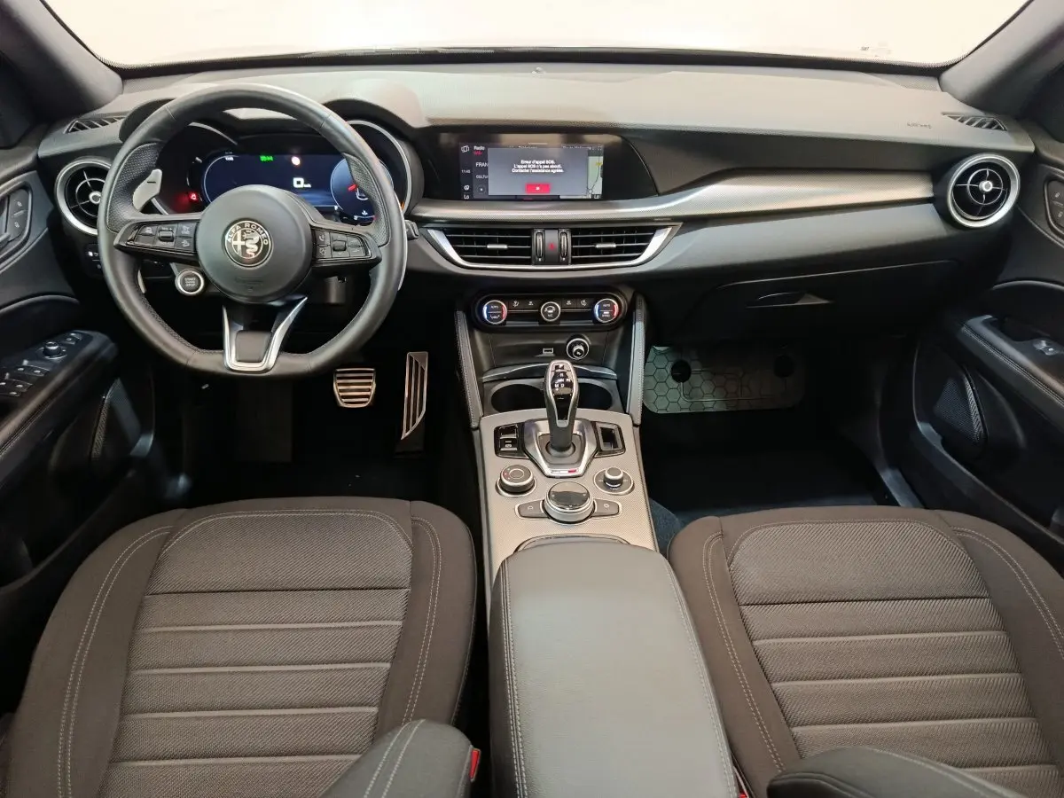 Vue intérieure avant de l'Alfa Romeo Stelvio 2.2 TD 160 AT8 Sprint 2024, tableau de bord noir avec écran tactile central.