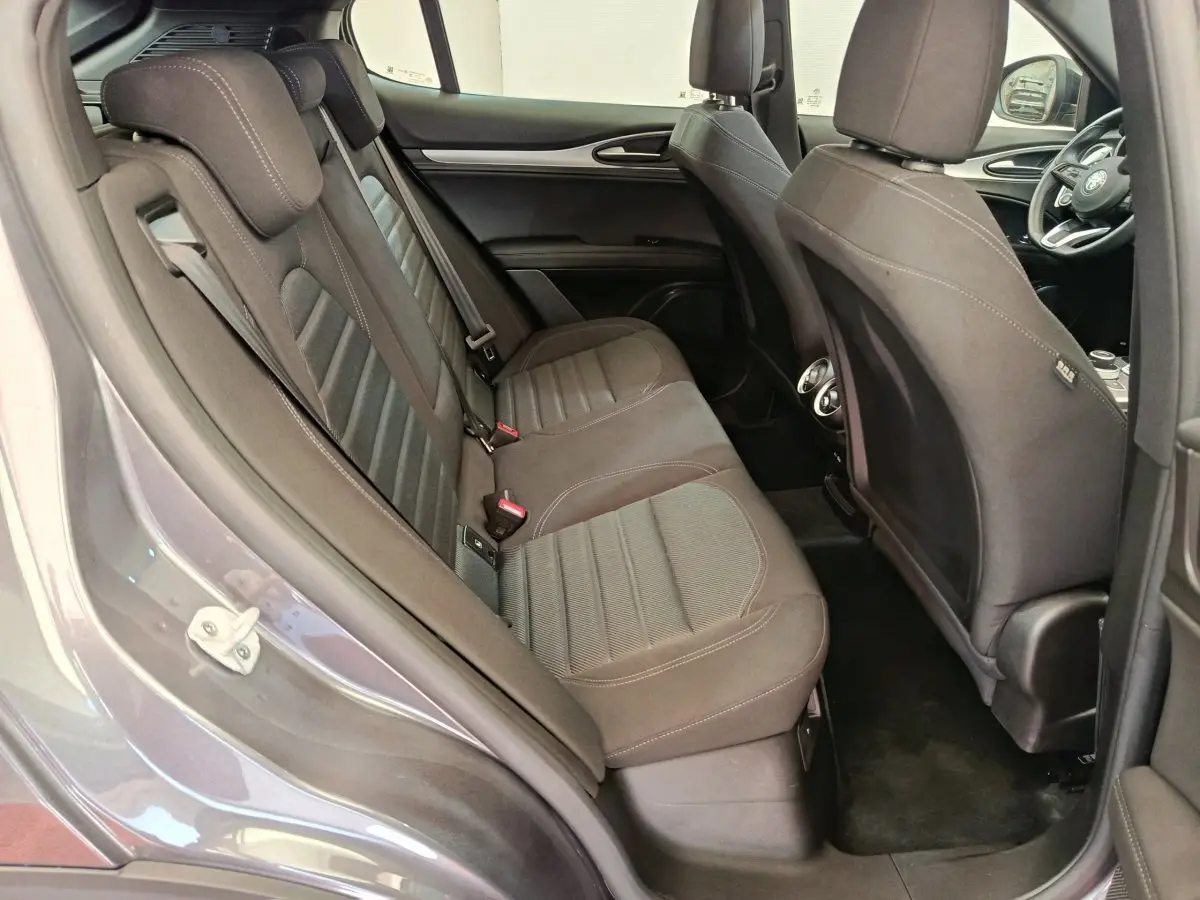 Vue intérieure côté gauche des sièges arrière gris foncé de l'Alfa Romeo Stelvio 2024 avec détails des appuie-têtes et portières.