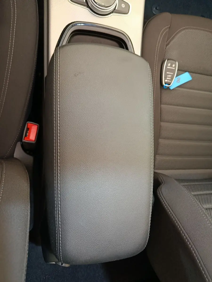 Vue plongeante sur l'accoudoir central en cuir noir et la clé de voiture posée sur le siège conducteur d'un Alfa Romeo Stelvio gris foncé.