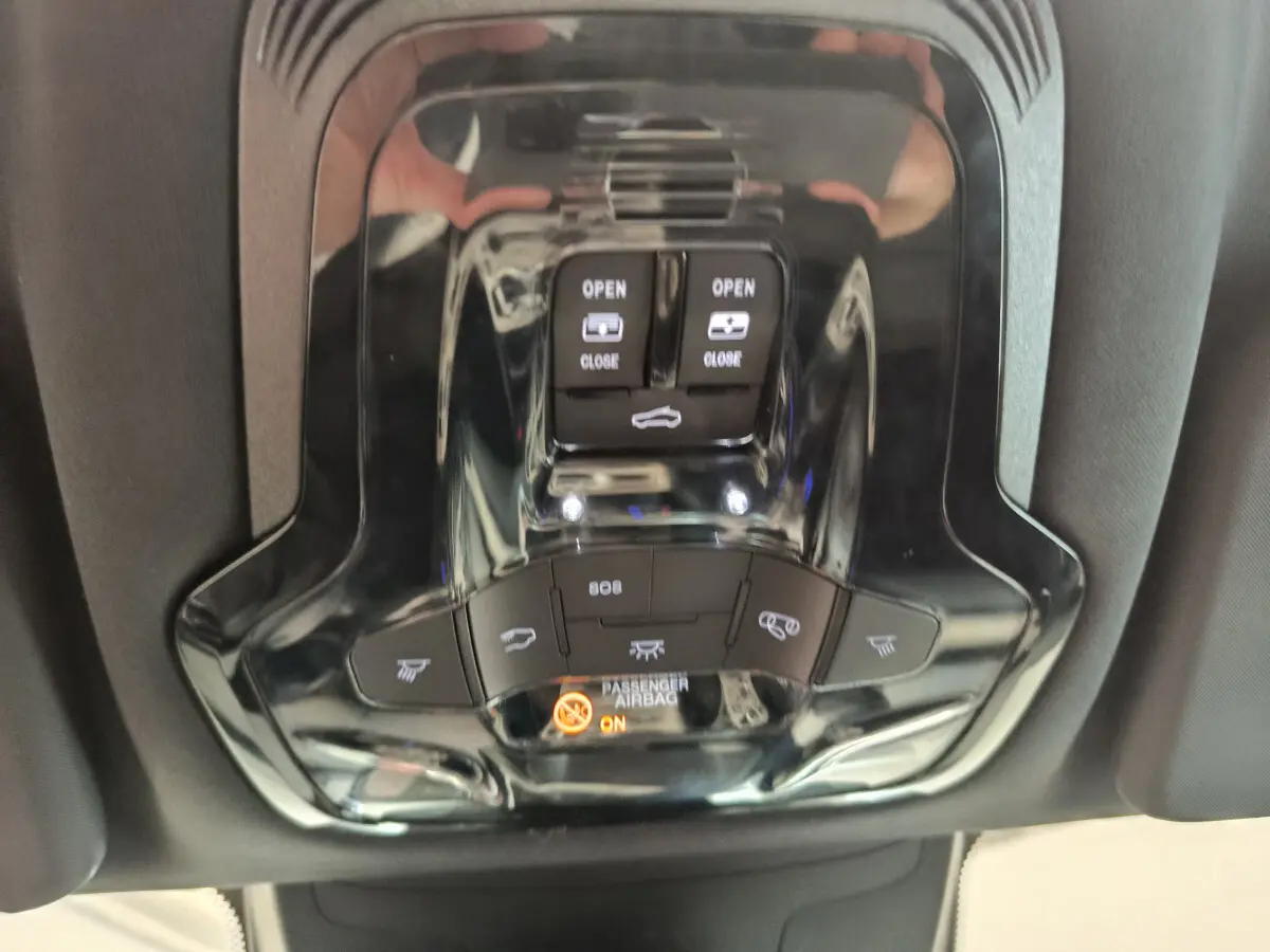 Gros plan sur la console de toit noire brillante de l'Alfa Romeo Stelvio 2024 avec commandes d'ouverture et voyants airbag.
