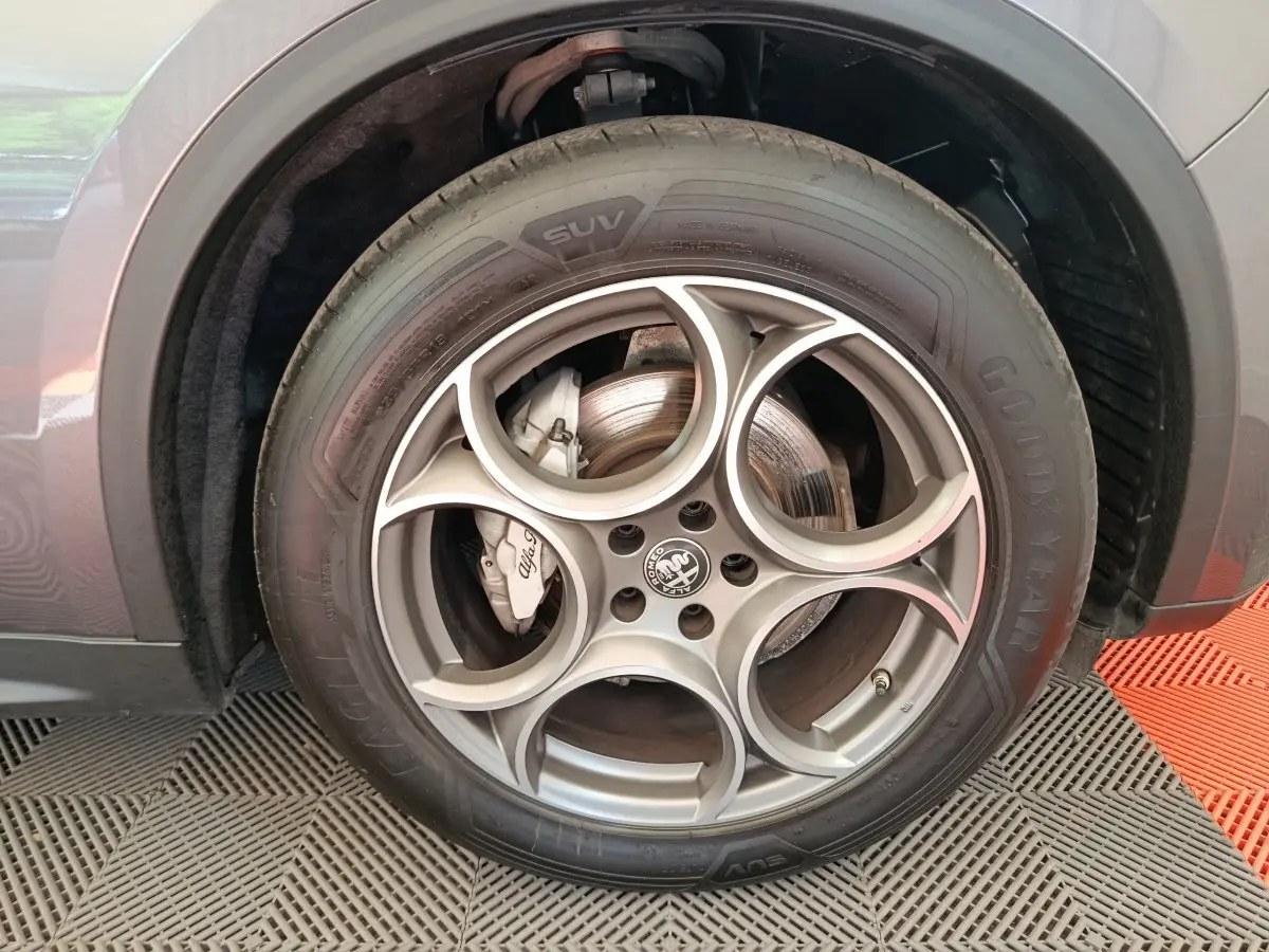 Gros plan sur la roue avant gauche gris foncé de l'Alfa Romeo Stelvio 2024 avec jante en alliage à motif circulaire distinctif.
