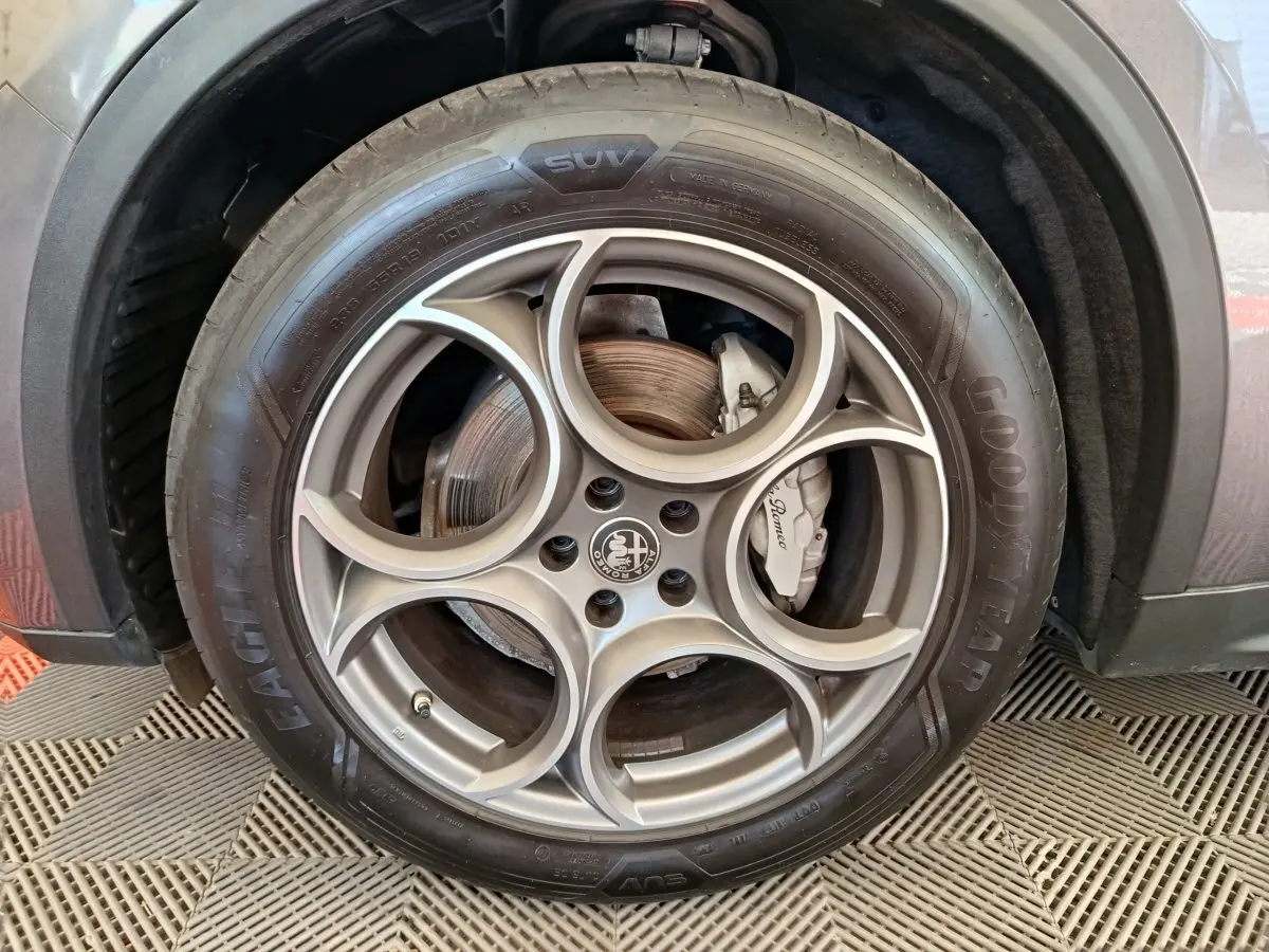 Gros plan sur la roue avant droite gris foncé d’un Alfa Romeo Stelvio avec jante en alliage et logo central distinctif.