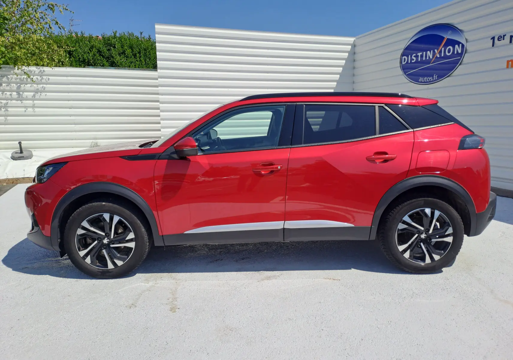 Profil droit du SUV Peugeot 2008 rouge 2021 avec jantes alliage noires et détails noirs sur les ailes et toit.