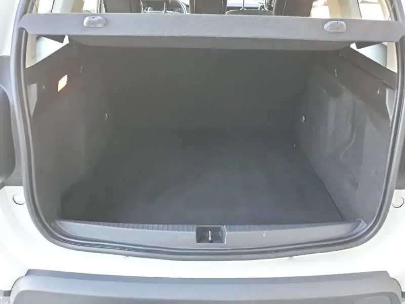 Coffre ouvert vu de l'arrière d'un Dacia Duster blanc 2021, montrant un espace de chargement vide et propre.