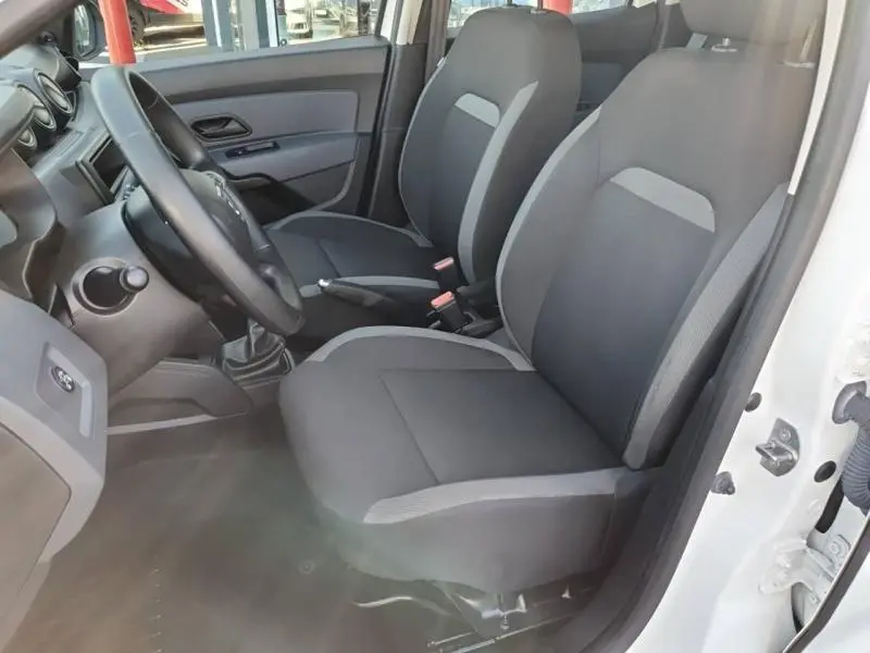 Vue intérieure côté gauche du Dacia Duster 2021 blanc, montrant les sièges avant en tissu gris et noir et le volant.