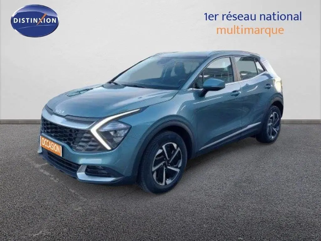 Vue 3/4 avant d'un KIA Sportage gris Sirius metal avec feux LED en forme de flèche et jantes bi-ton.