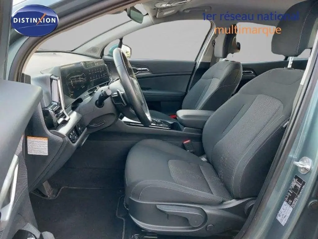 Intérieur avant droit du Kia Sportage 2024 gris Sirius Metal, sièges tissu noir et tableau de bord moderne.