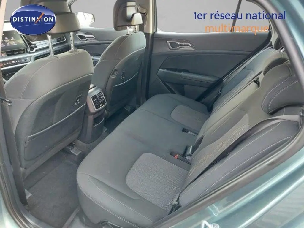 Vue intérieure arrière côté droit du Kia Sportage 2024, sièges tissu noir avec surpiqûres grises, ambiance sobre et moderne.