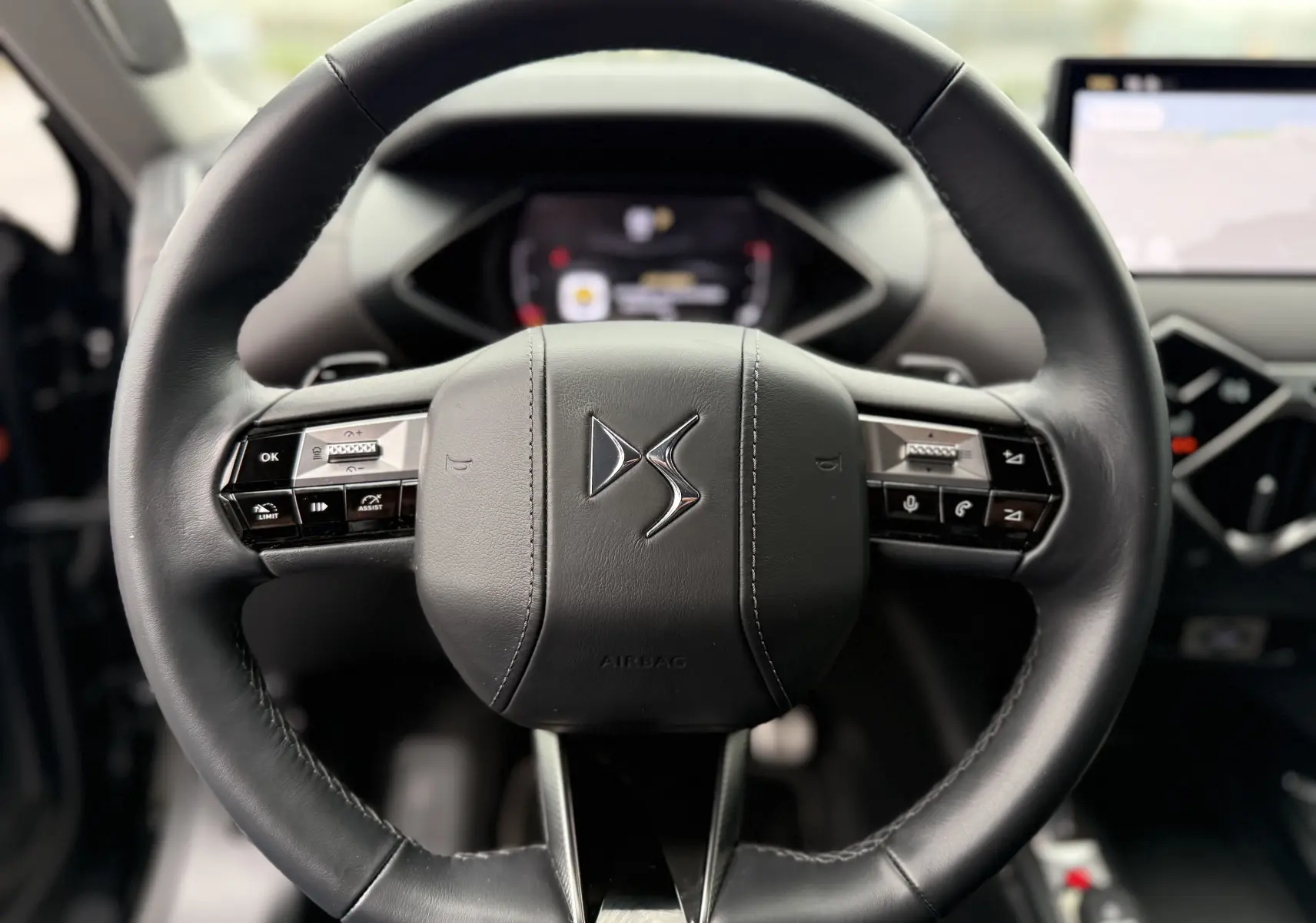 Gros plan sur le volant en cuir noir du DS3 2024, avec commandes intégrées et logo DS au centre.