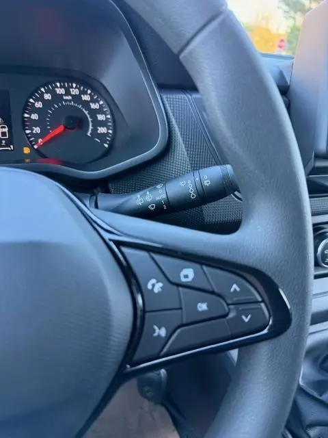 Gros plan sur le volant multifonctions gris du Renault Trafic Fourgon 2025 avec tableau de bord et commandes visibles.