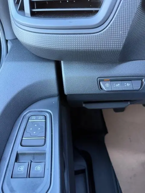 Détail des commandes de vitres électriques et boutons de fonctions sur la porte côté conducteur du Renault Trafic Fourgon gris clair 2025.