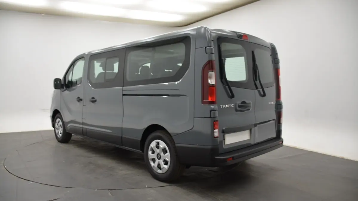 Vue 3/4 arrière droite du Renault Trafic Fourgon gris clair 2025 avec vitres latérales et portes arrière battantes.